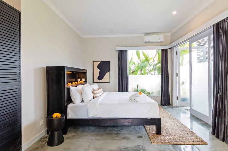 Bedroom with dark timber headboard opening to the garden